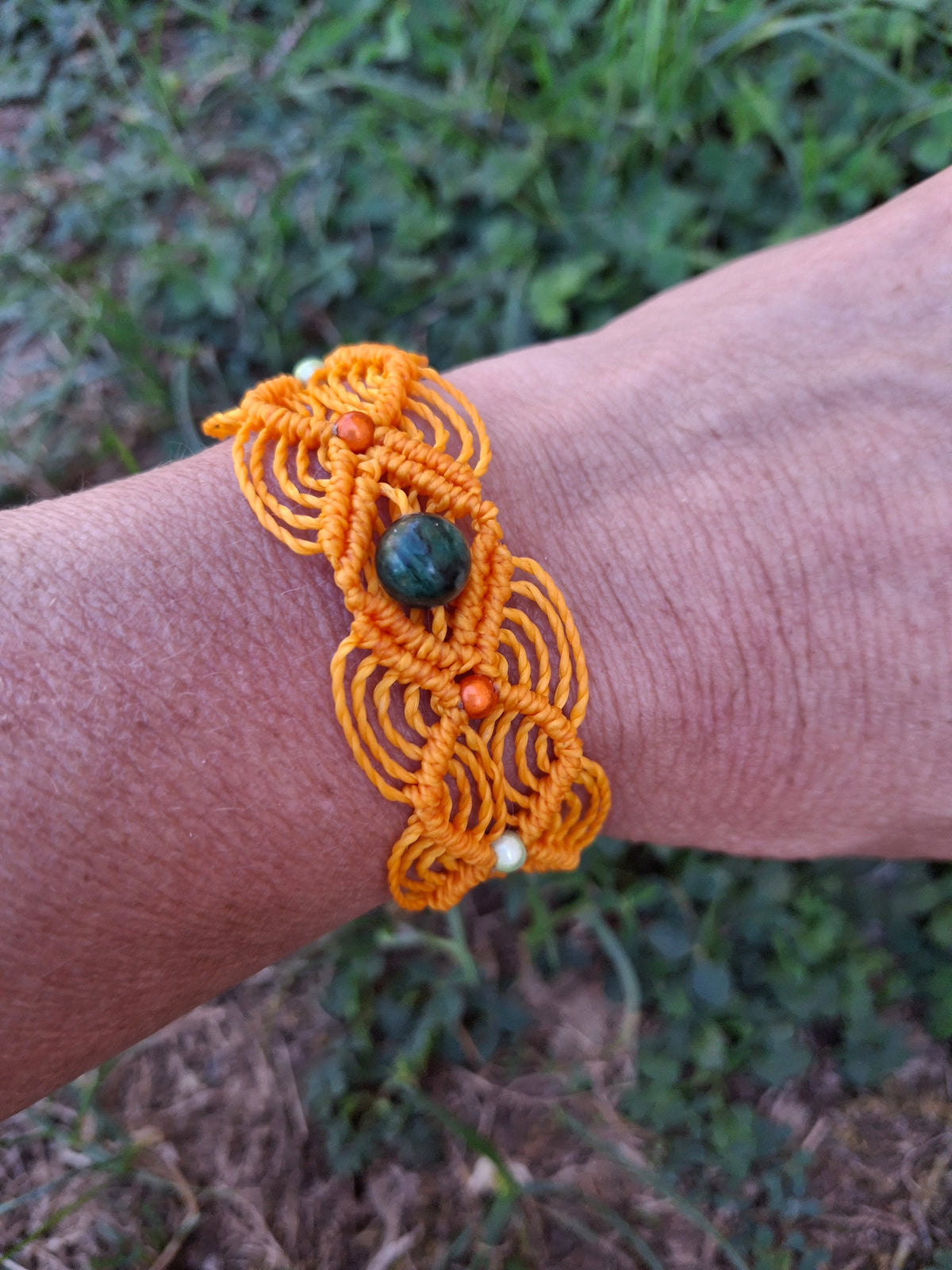 bracelet tissé à la main en micro macramé de couleur orange clair avec une perles de 8 mm en émeraude et des perles réfléchissante