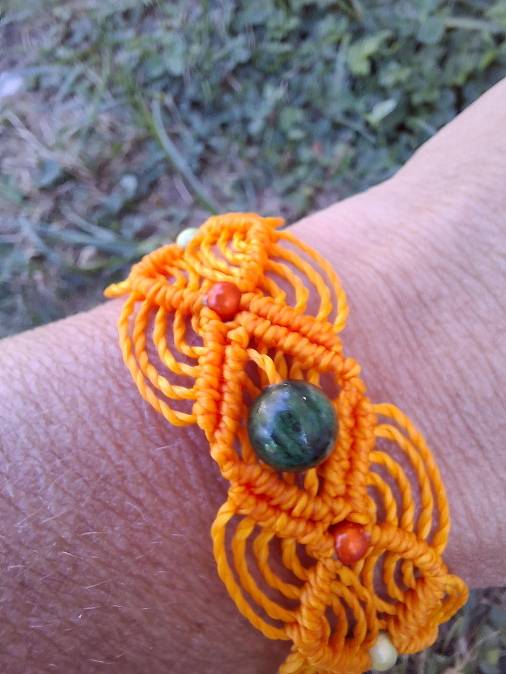 bracelet tissé à la main en micro macramé de couleur orange clair avec une perles de 8 mm en émeraude et des perles réfléchissante