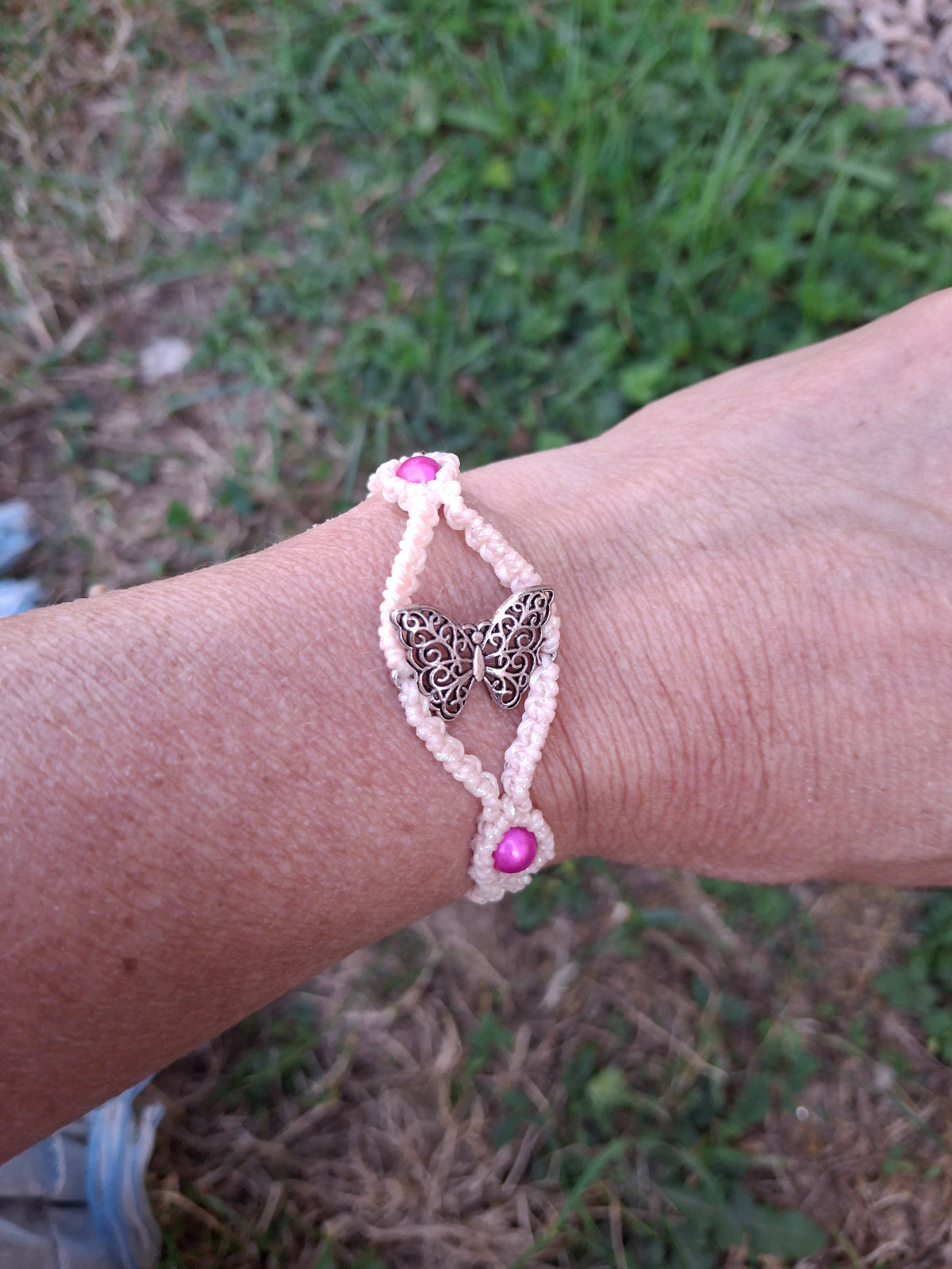 bracelet tissé à la main en micro macramé de couleur flamant rose iridescent avec un papillon en alliage de zinc et 2 perles réfléchissante  rose foncé