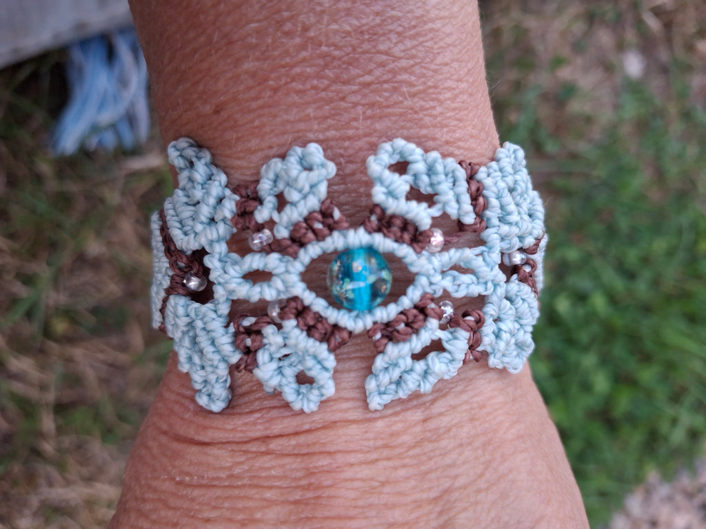 bracelet tissé à la main en micro macramé de couleur menthe et chocolat avec une perle fluorescente  en verre  bleu et des perles de rocailles fluorescente 