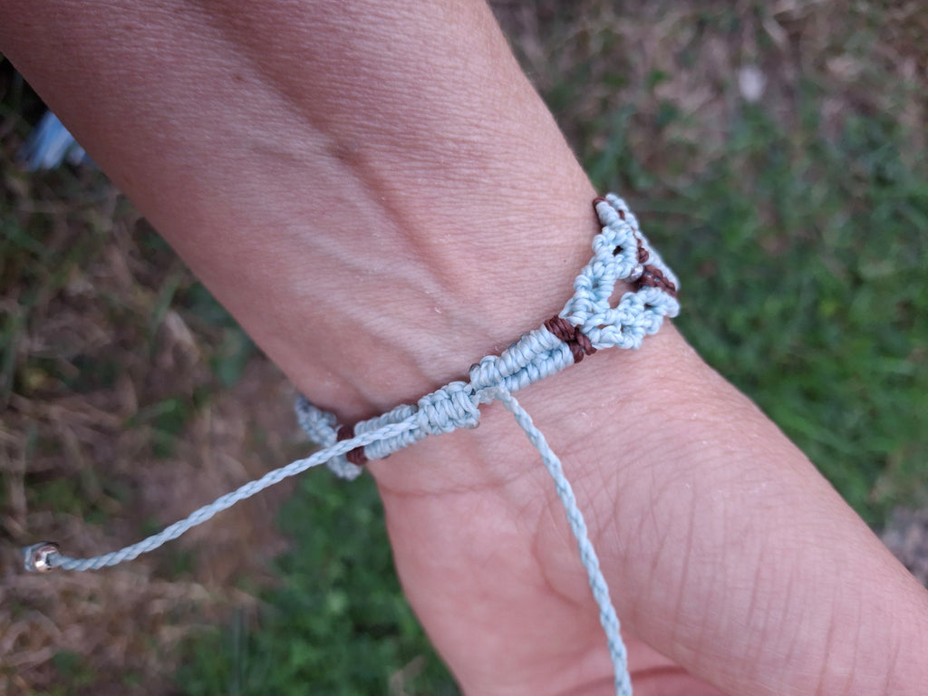 bracelet tissé à la main en micro macramé de couleur menthe et chocolat avec une perle fluorescente  en verre  bleu et des perles de rocailles fluorescente 