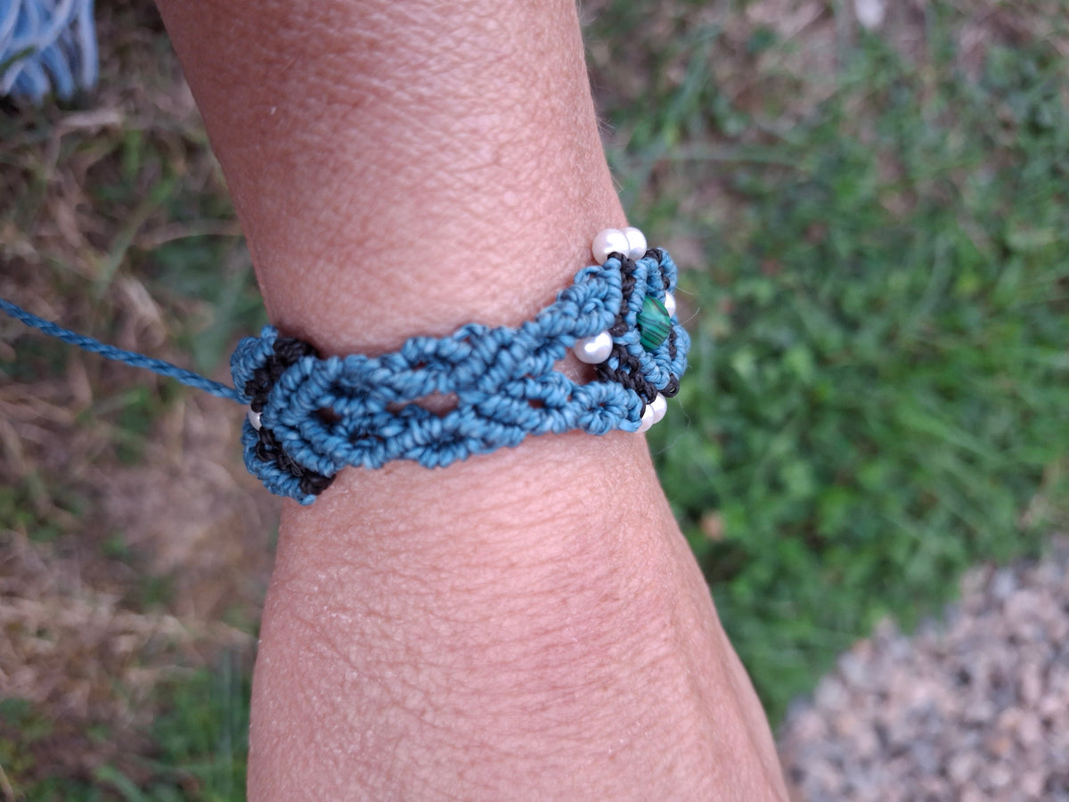 bracelet tissé à la main en micro macramé de couleur bleu canard et noir avec une perle fantaisie verte de 6mm et des perles en acrylique blanche