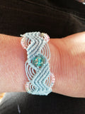 bracelet modèle @solyluna tissé a la main en micro macramé de couleur azur clair avec une perle en verre fluorescente.
