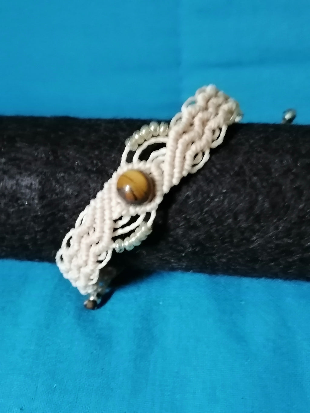 bracelet modèle @solyluna tissé a la main en micro macramé de couleur beige avec une perle en oeil de tigre.
