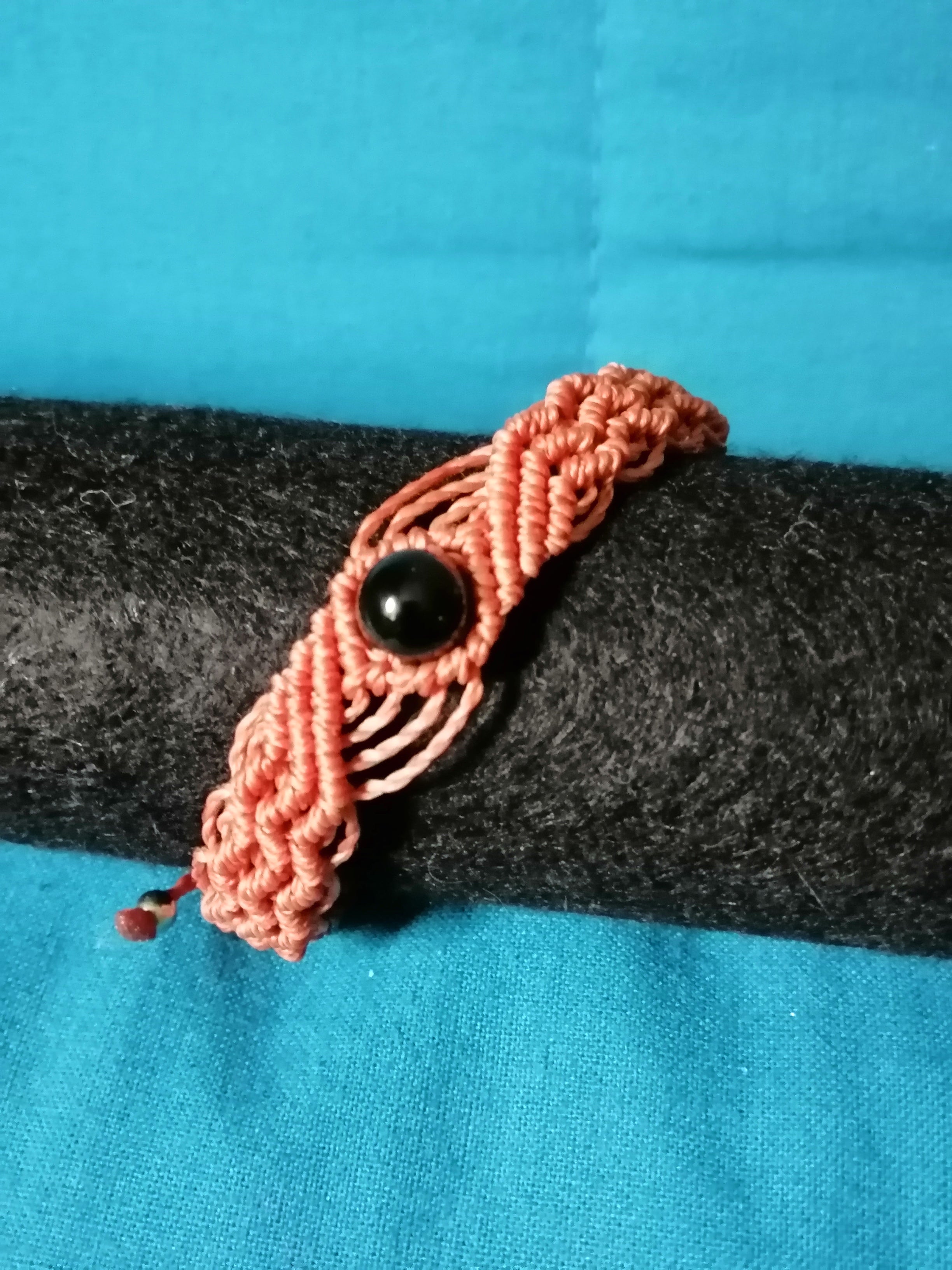 bracelet modèle @solyluna tissé a la main en micro macramé de couleur brique avec une perle en obsidienne.