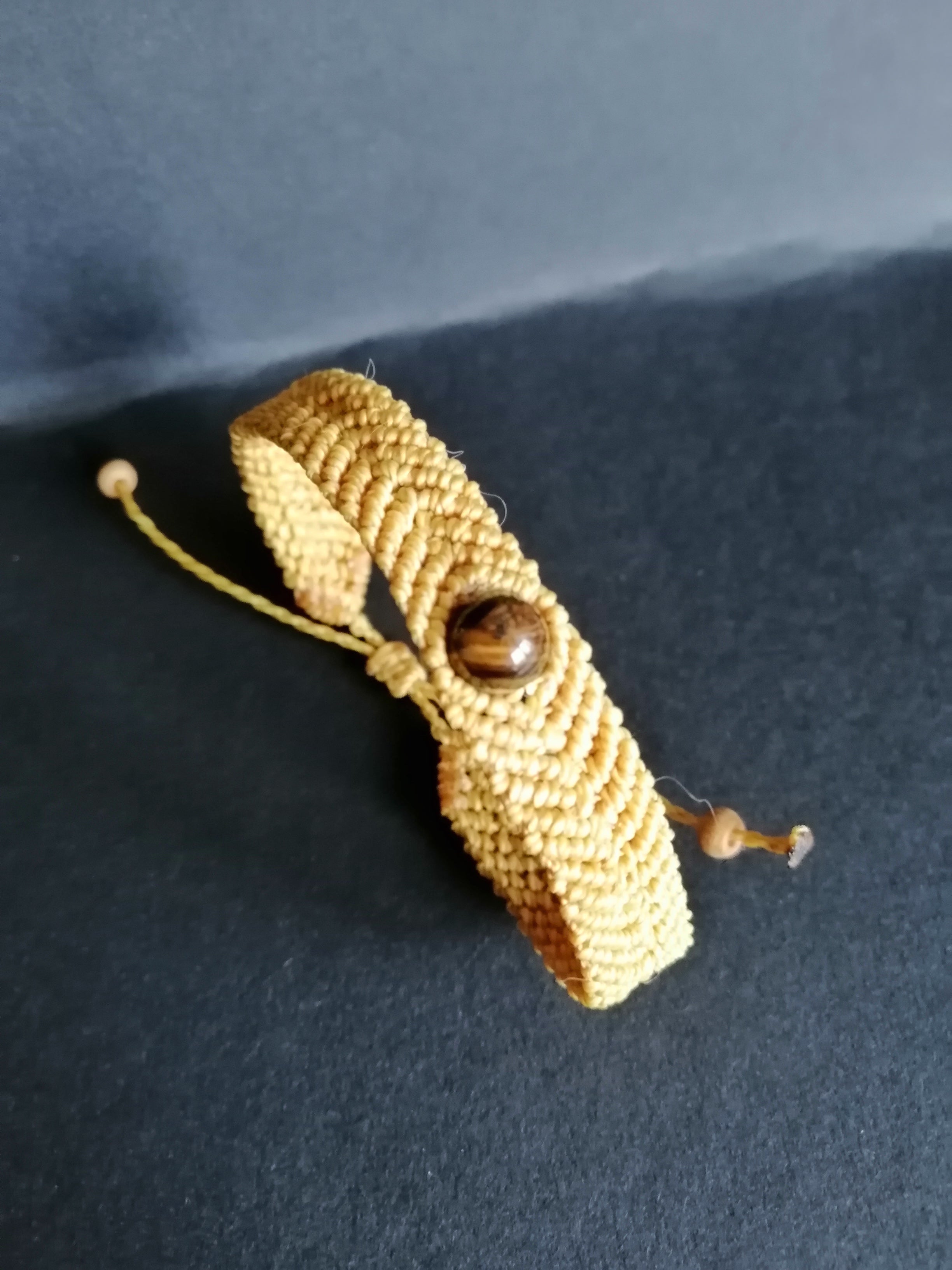 bracelet tissé a la main en micro macramé de couleur moutarde avec une perle en oeil de tigre.