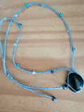 sautoir tissé a la main en micro macramé de couleur bleu ciel avec des perles en verre, des perles réfléchissante et une pierre en labradorite bleu.