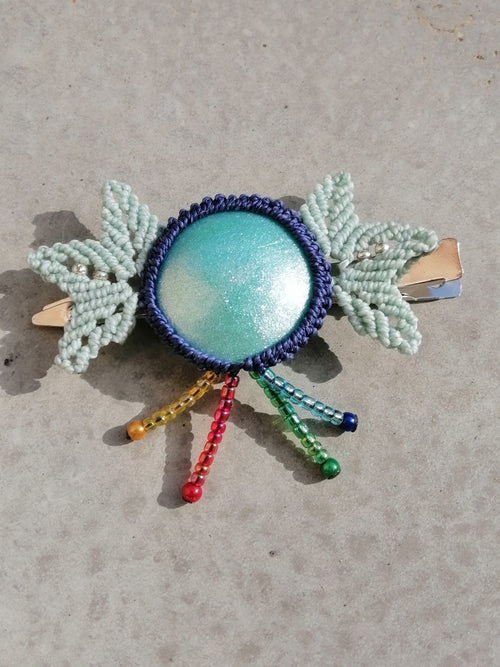 barrette avec pince crocodile ,un cabochon en résine époxy de couleur turquoise sertie en micro macramé de couleur bleu marine et des feuilles menthe de chaque coté