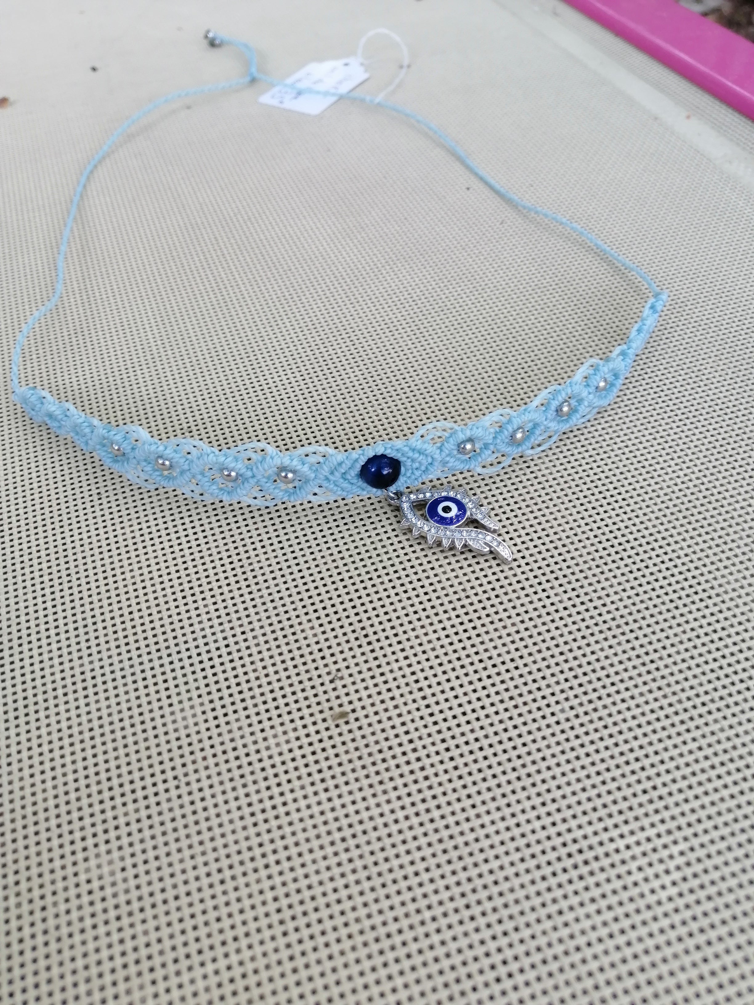choker tissé à la main en micro macramé de couleur azur clair avec un oeil de tigre teinté bleu et l'oeil grec pendant