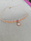 choker tissé à a main en micro macramé de couleur mandarine et sable, une perle de 8mm et un soleil