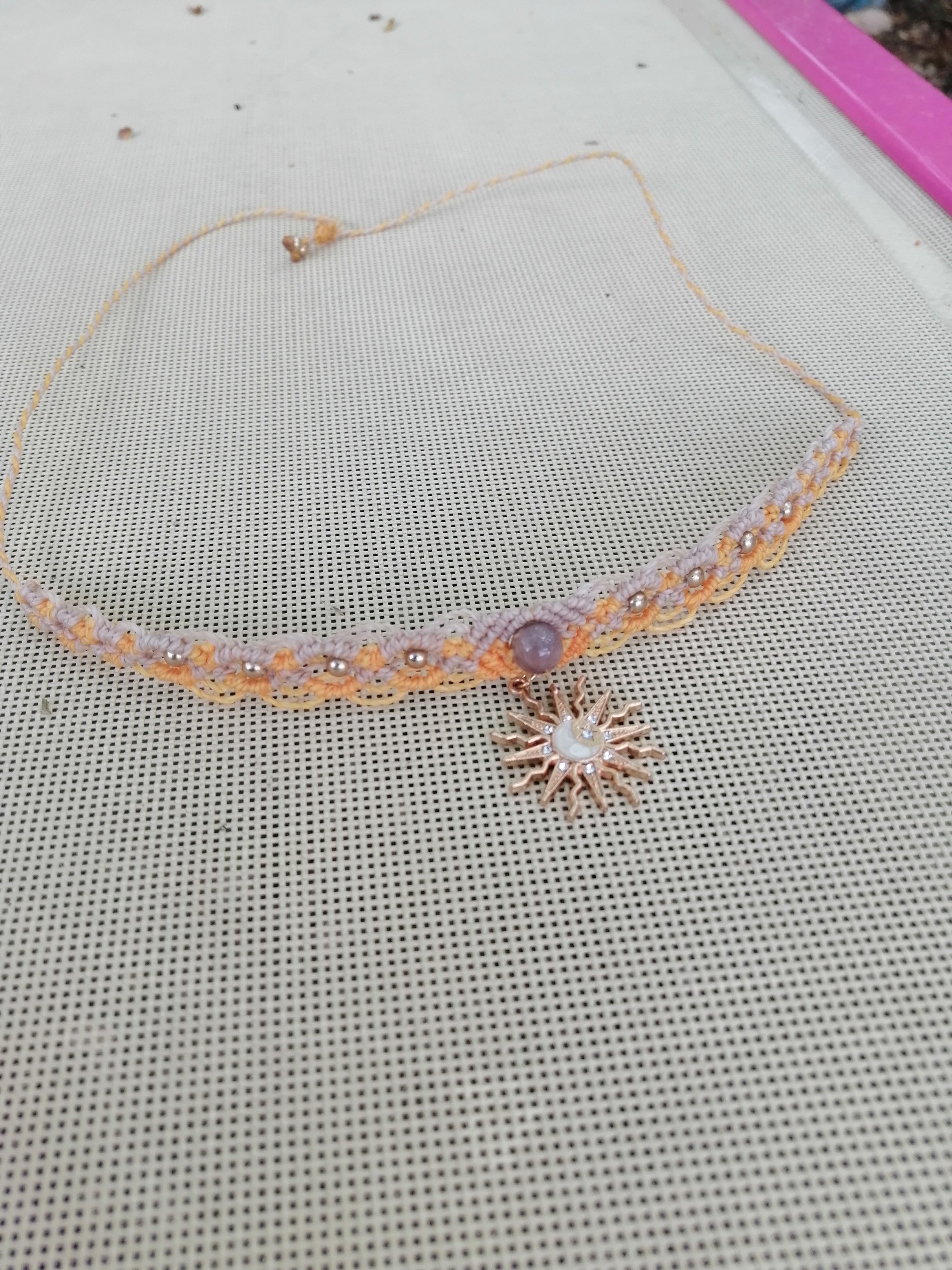 choker tissé à a main en micro macramé de couleur mandarine et sable, une perle de 8mm et un soleil