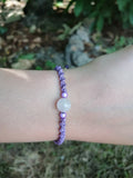 bracelet enfant tissé à la main en micro macramé de couleur mauve avec une perle en  quartz rose et 2 perles réfléchissante de couleur mauve