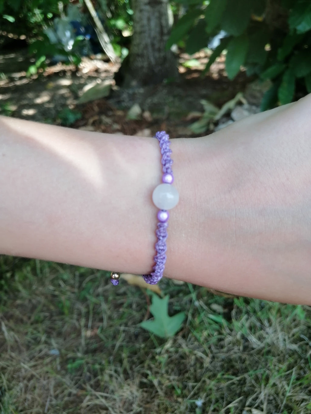 bracelet enfant tissé à la main en micro macramé de couleur mauve avec une perle en  quartz rose et 2 perles réfléchissante de couleur mauve