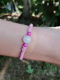 bracelet enfant tissé à la main en micro macramé de couleur bois de rose avec une perle en quartz rose et 2 perles réfléchissante rose