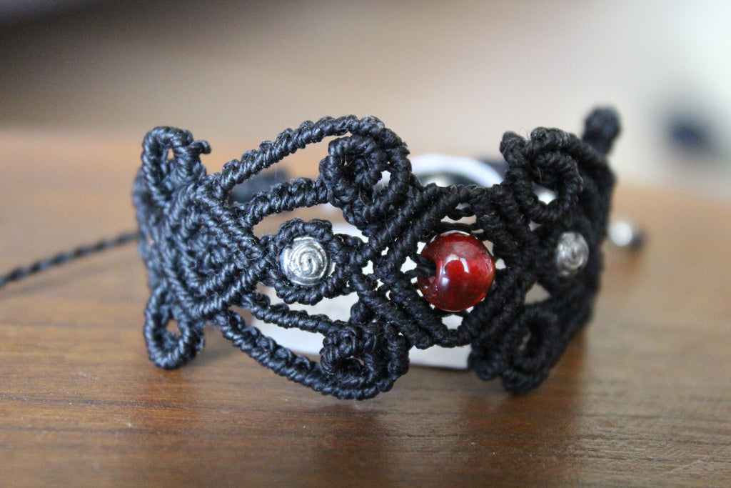 bracelet modèle @lesfilsambulants tissé a la main en micro macramé de couleur noir avec des perles en acrylique et une en verre.