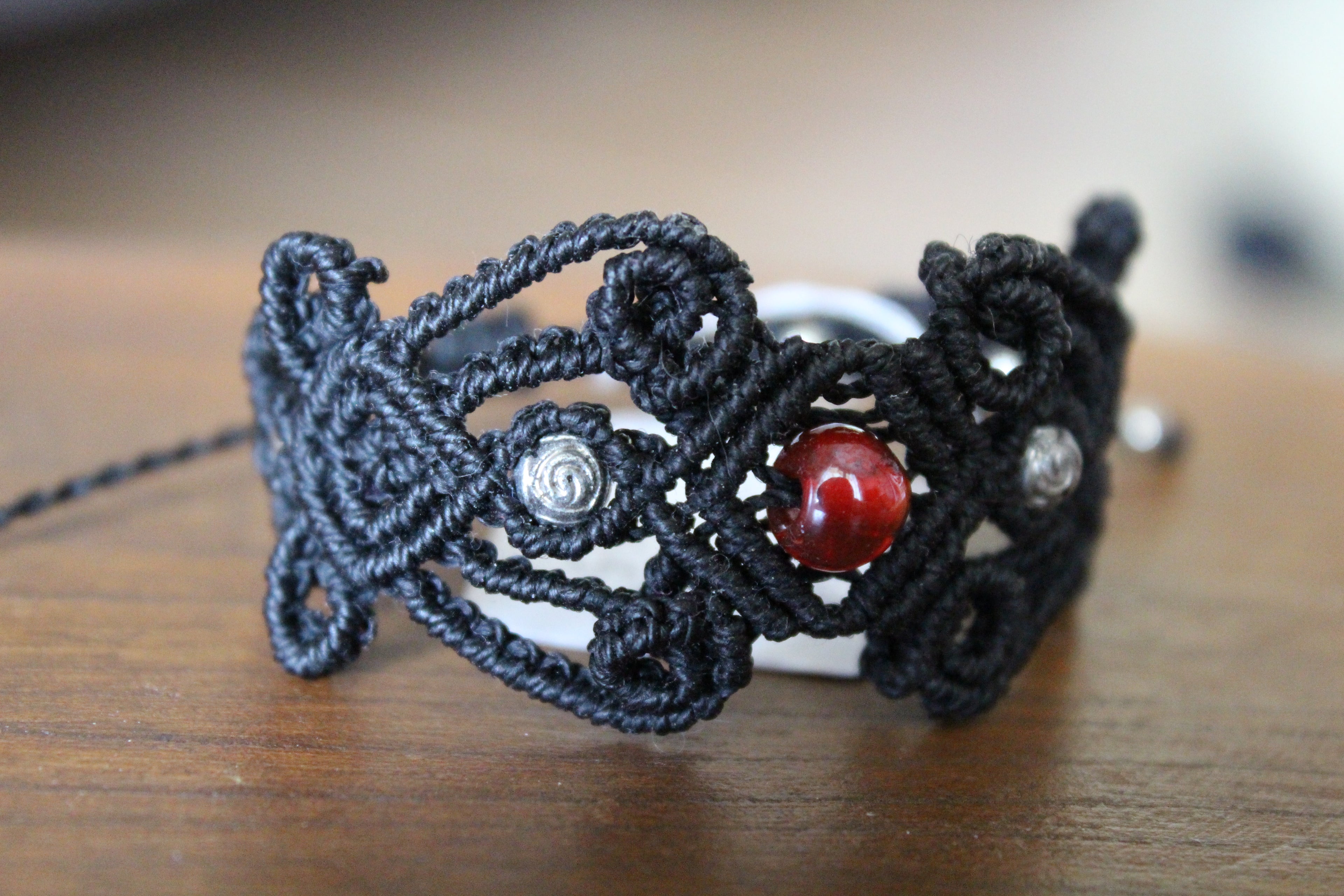 bracelet modèle @lesfilsambulants tissé a la main en micro macramé de couleur noir avec des perles en acrylique et une en verre.