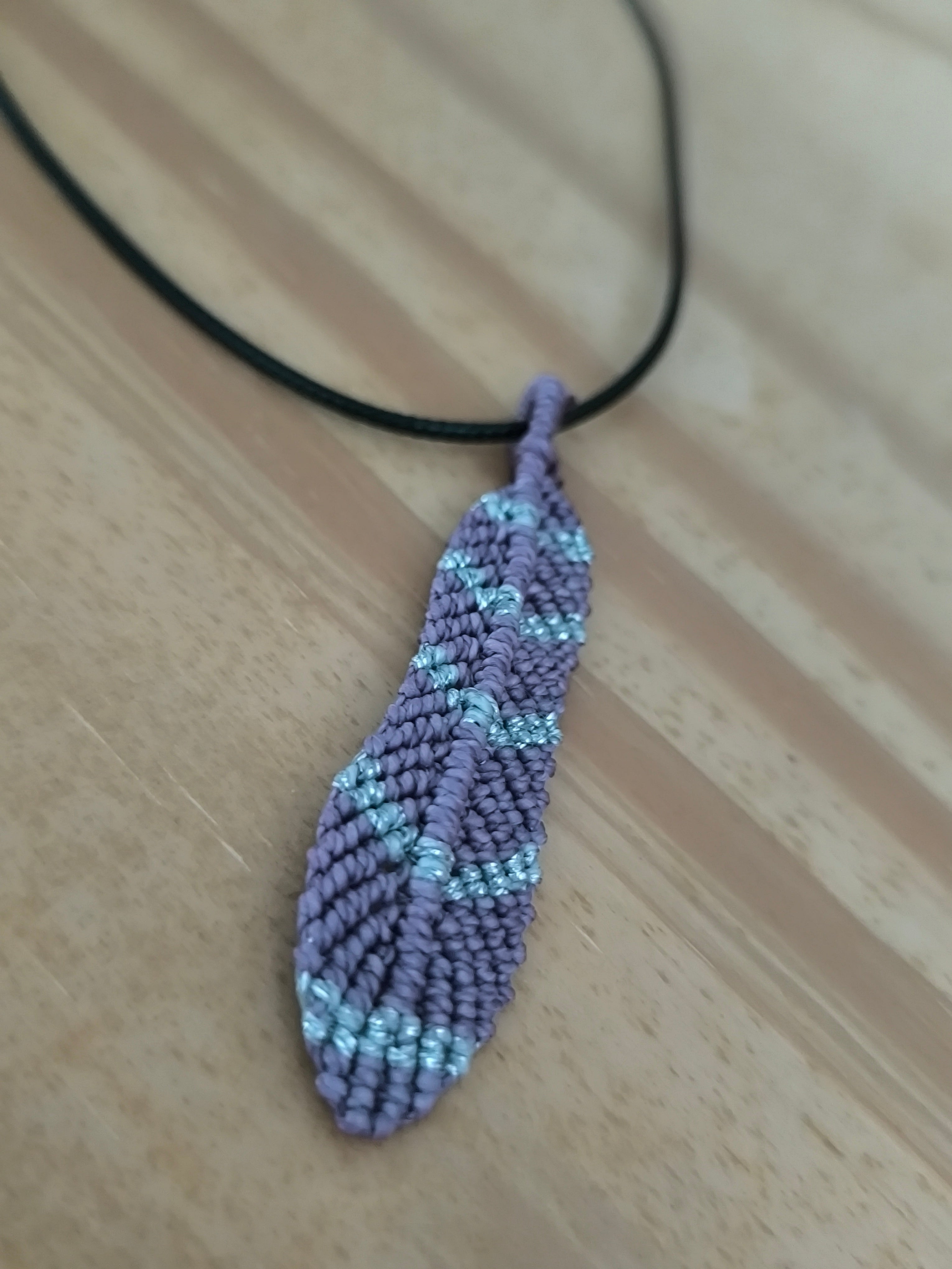 cordon de cuir noir avec une plume tissé a la main en micro macramé de couleur mauve et argenté.