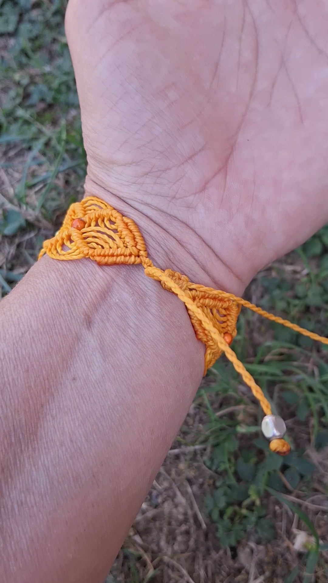 bracelet tissé à la main en micro macramé de couleur orange clair avec une perles de 8 mm en émeraude et des perles réfléchissante