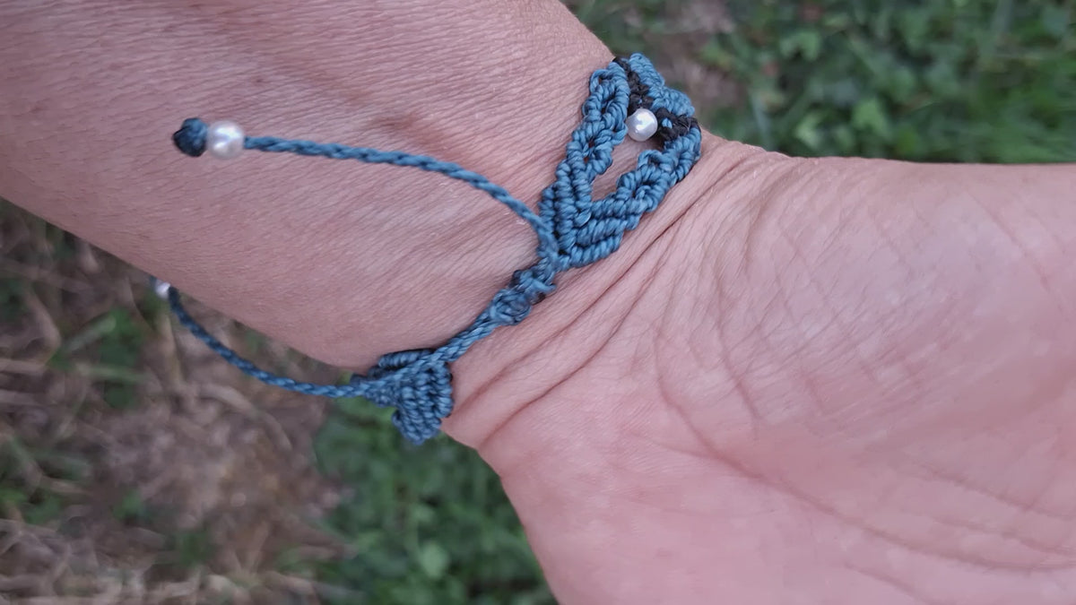 bracelet tissé à la main en micro macramé de couleur bleu canard et noir avec une perle fantaisie verte de 6mm et des perles en acrylique blanche